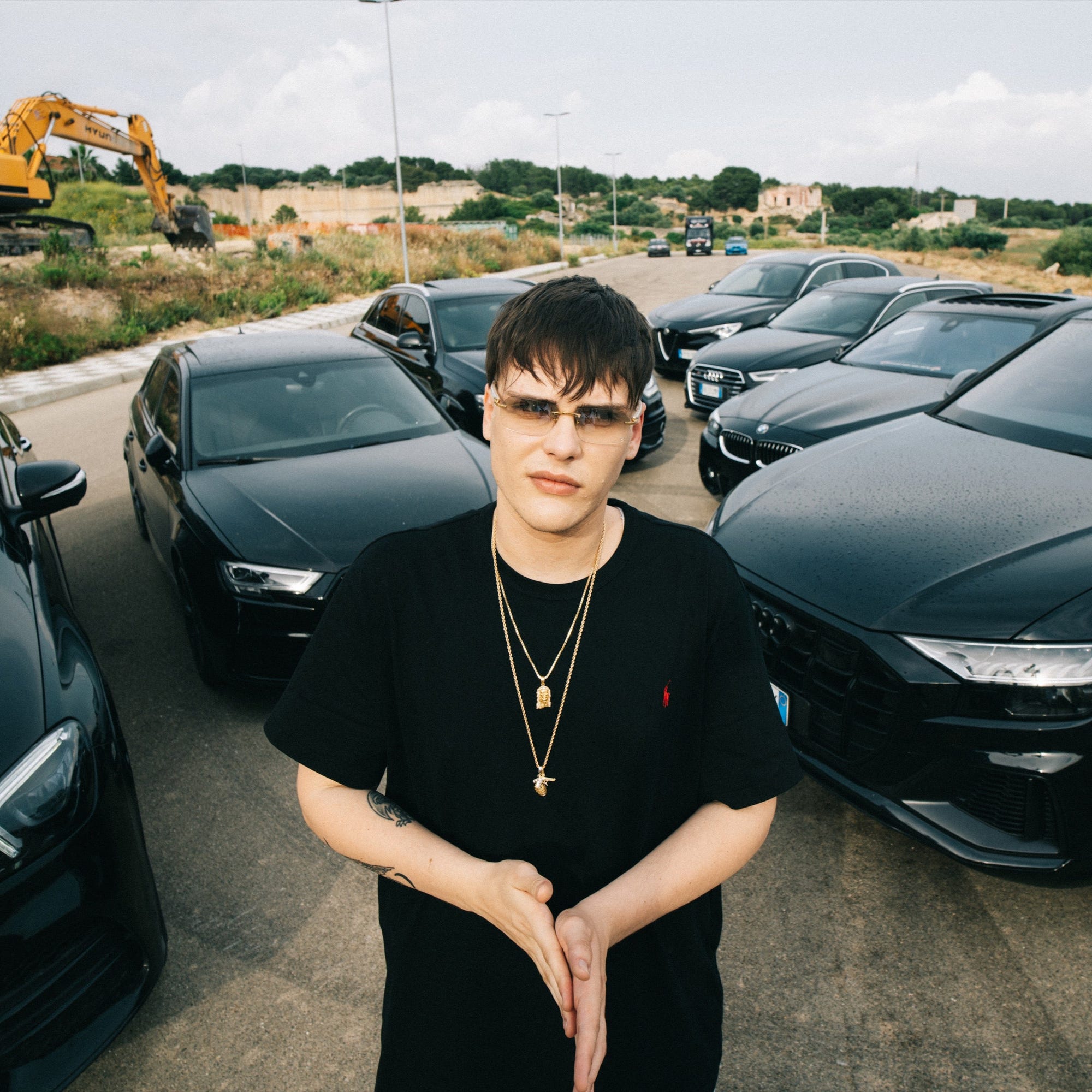 FOTO PROFILO ARTISTA KID YUGI RAPPER PUGLIESE IN PRIMO PIANO MEZZO BUSTO CON AUTO NERE SULLO SFONDO