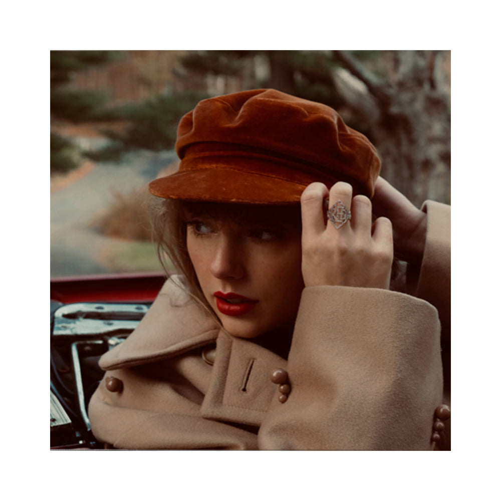 copertina dell'album red di taylor swift foto della cantante in primo piano con cappellino rosso e trench beige seduta su un'automobile